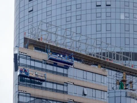 Builders in a building suspension platform working at a very high altitude Stock Photos