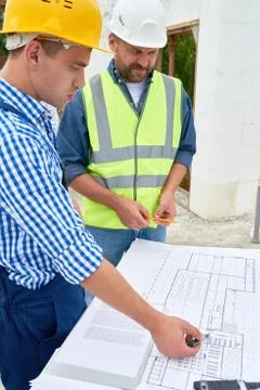 Builders Checking Floor Plans on Construction Site 写真素材
