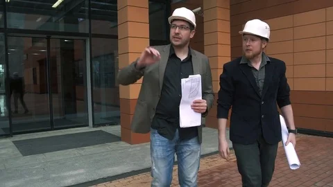 Builders at the construction site. Architects go in construction helmets to a Stock Footage 75356888