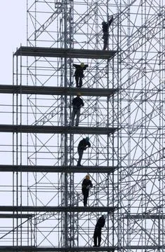 Builders Constructive work builds on a metal stand structure. Copyright: x... Stock Photos