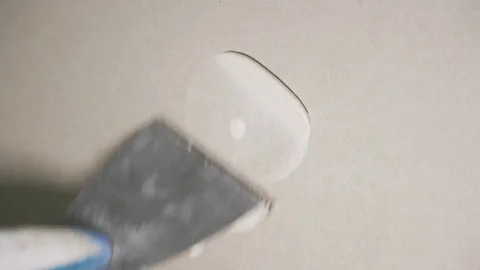 Builders cover up a self-tapping screw in drywall with a spatula with putty Vídeos de archivo 212830702