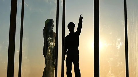 Builders discuss construction and work details silhouette in window frame Stock Footage 89923692