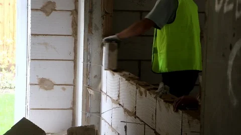 Builders discuss work whilst removing breeze blocks from wall Stock Footage 112609478