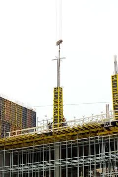 Builders fix the structure suspended from the hook of a crane on the top of t Stock Photos
