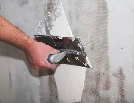 Builders float in hand applying putty on the wall Stock Photos