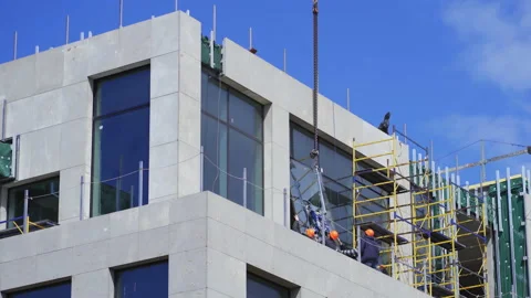 Builders glazed a new constructed building hold the glass raised by a crane to Stock Footage 131382937