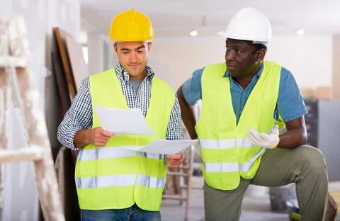 Builders having conversation about work plan in apartment Stock Photos