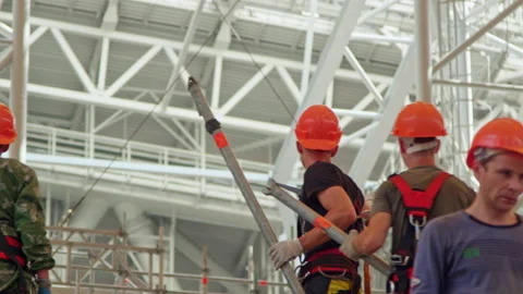 Builders with helmets work with metal tubes for pipeline Stock Footage 238936427