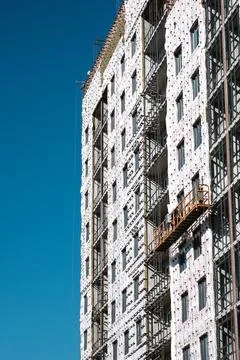 Builders on an industrial elevator are engaged in cladding and insulation of Stock Photos