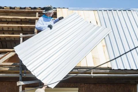 Builders lay a galvanized sheet of iron on the roof of the house Foto stock