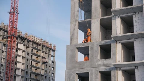 Builders mount concrete wall panels lifted by tower crane Stock Footage 124299280