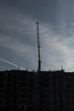 Builders move across rooftop of unfinished multi story building Stock Photos