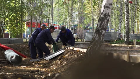 Builders pull pipe under new paved road in green park Stock Footage 267391206