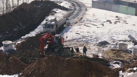 Builders using an excavator build a sewage system for the apartment building Stock-Footage 74110387