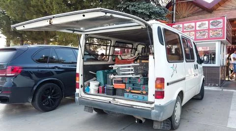 Builders van filled with tools is parked on the street. Builder equipment and Stock Photos