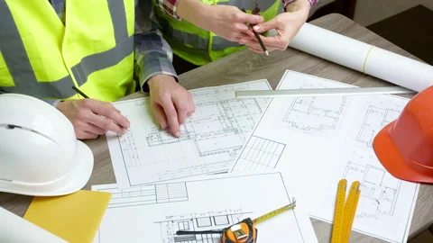 Builders work with blueprints discussing at the desktop. Architects at work. Stock Footage 221330247