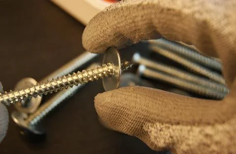 Builder's work process. Putting the washer on the screw. Stock Photos