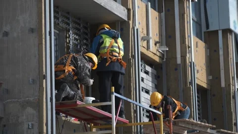 Builders work on scaffolding in uniform and safety helmets. Construction. Stock Footage 321004572