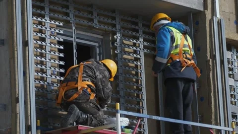 Builders work on scaffolding in uniform and safety helmets. Construction. Stock Footage 321004665