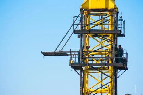 Builders work on yellow crane at construction site Foto stock