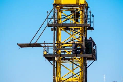 Builders work on yellow crane at construction site Stock Photos