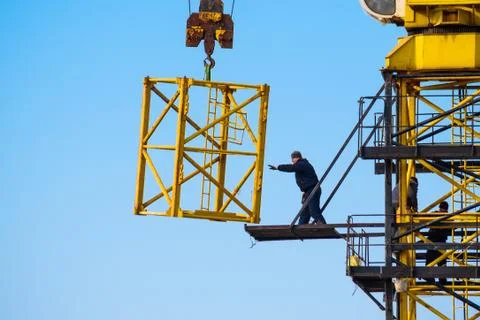Builders work on yellow crane at construction site Stock Photos