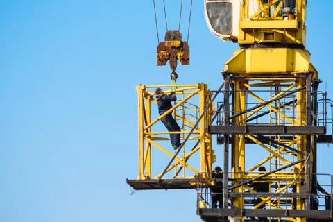 Builders work on yellow crane at construction site Foto stock