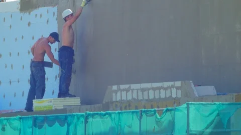 Builders working on facade thermal insulation and applying mortar over an Stock Footage 108432927