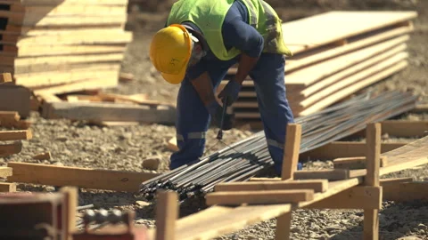 Builders in yellow helmets and yellow vests work at a construction site Stock Footage 246762197