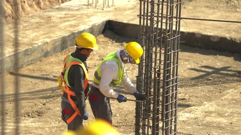 Builders in yellow helmets and yellow vests work at a construction site Stock Footage 246762853