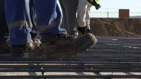 Builders in yellow helmets and yellow vests work at a construction site Stock Footage 246764086