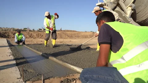Builders in yellow helmets and yellow vests work at a construction site Stock Footage 246764284