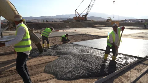 Builders in yellow helmets and yellow vests work at a construction site Stock Footage 246764701