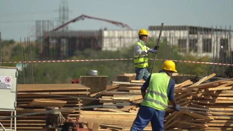 Builders in yellow helmets and yellow vests work at a construction site Stock Footage 246765278
