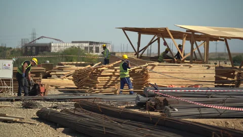 Builders in yellow helmets and yellow vests work at a construction site Stock Footage 246765424