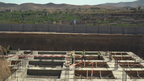 Builders in yellow helmets and yellow vests work at a construction site Stock Footage 246765454