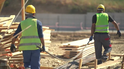 Builders in yellow helmets and yellow vests work at a construction site Stock Footage 246765669