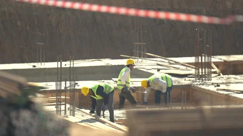 Builders in yellow helmets and yellow vests work at a construction site Stock Footage 246765922