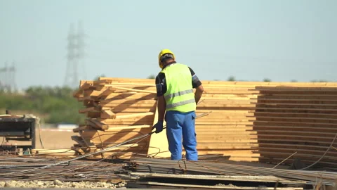Builders in yellow helmets and yellow vests work at a construction site Stock Footage 246766015