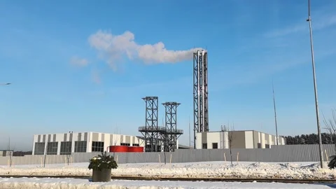 Building and smoke stack in snowy industrial area with clear blue sky in winter Stock Footage 328487470