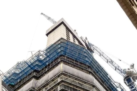 Building with a blue crane undergoing construction with a white sky backgroun Stock Photos