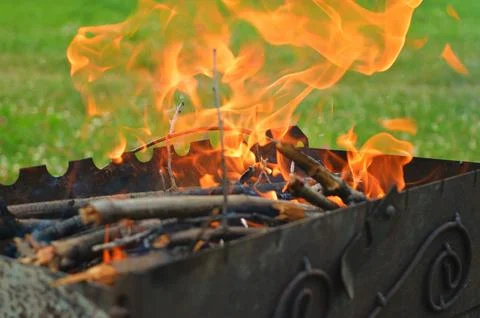 Building a bonfire inside a metal rectangular brazier. Firewood is burning .. Stock Photos