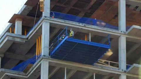 Building construction workers on landing handle huge glass pane lowered by crane 動画素材 152802130