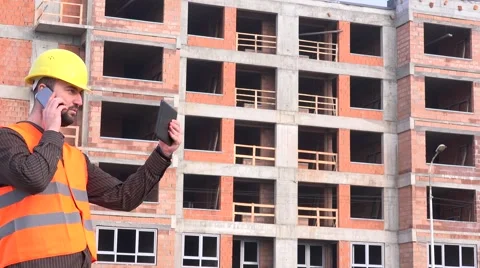 Building contractor outside construction site talking to developer mobile phone Stock Footage 58513894