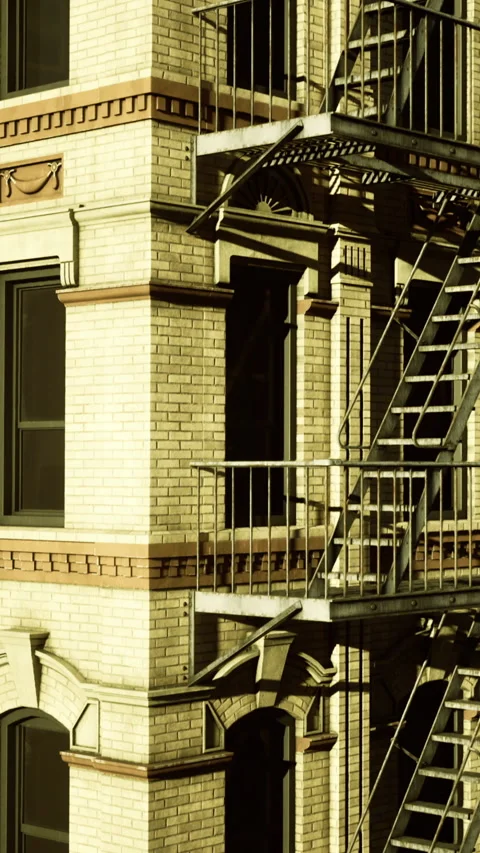 Building corner with fire escape and windows at sunset in a city Stock Footage 331687145