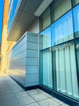Building corner with large windows and curtains in urban setting during day.. Stock Photos