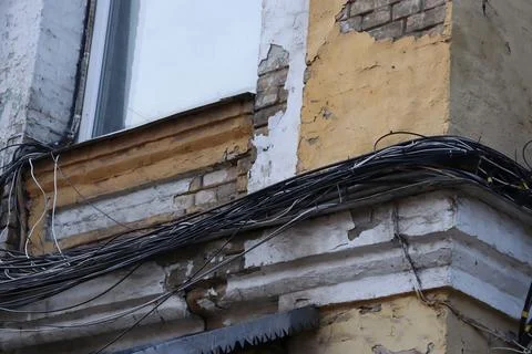 Building corner shows damage and wires near window in urban area during daytime Foto stock