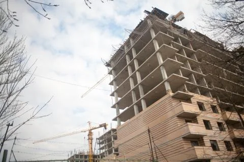 Building crane at the background of a multi-storey building under constructio Stock Photos