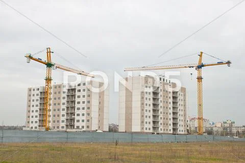 Building cranes above the unfinished apartment house. Stock Photos