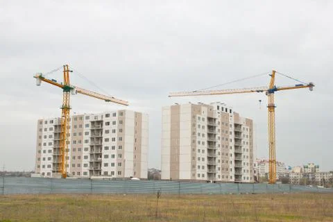 Building cranes above the unfinished apartment house. Stock Photos